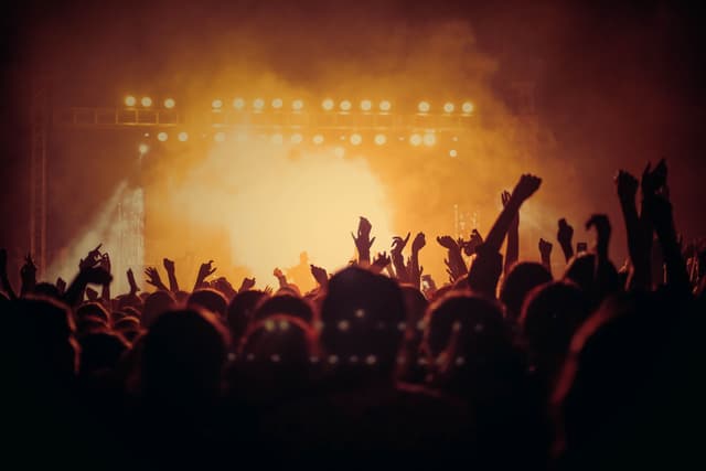 Multidão de mãos erguidas num show: o pico de demanda que o seu produto vai enfrentar quando der certo.